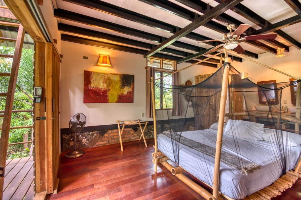 Wooden guest room with a mosquito-net bed at Selvista Guesthouses